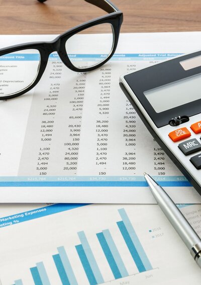 Image of bookkeeping spreadsheets with a calculator and glasses
