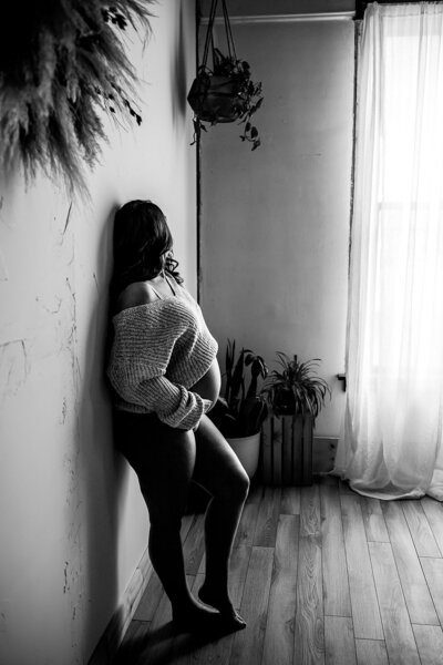 A momma embraces her growing baby bump with a flirty yet sexy knit sweater while her belly is the focus of a moody black and white print. 