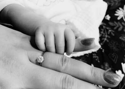 Hope's hand with her tiny newborn baby's hand.