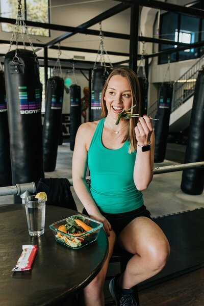 A woman enjoying a fresh salad while seated in a gym, promoting healthy eating habits in Lexington, KY.