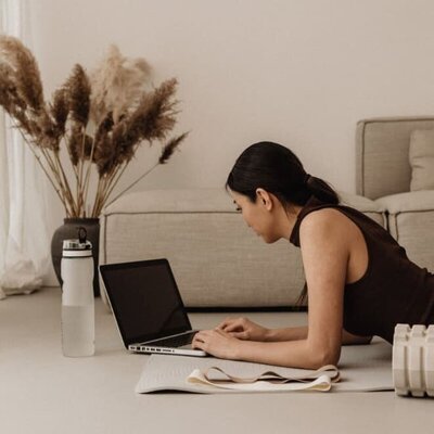 Woman lying on the floor working on a laptop, representing feeling overwhelmed by the fast-moving digital landscape