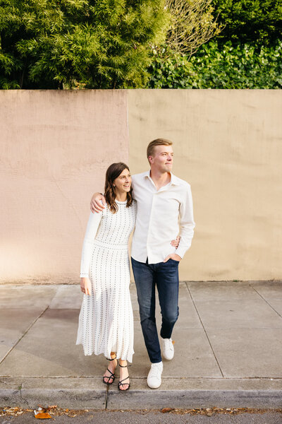 couple stands together in front of a multi-colored wall in san francisco
