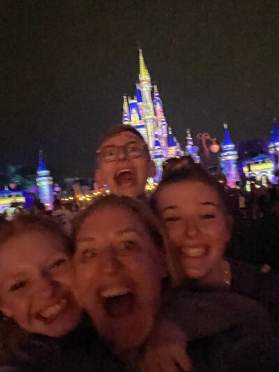 Tiffany and her children smiling in front of the castle at Disney World