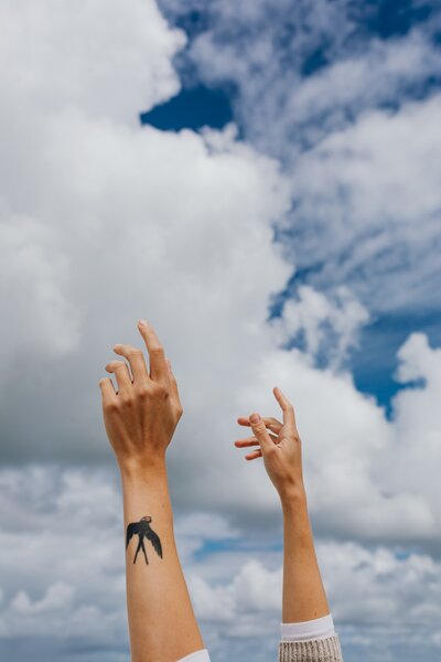 a person with hands up, feeling healed, in a blue sky full of clouds background