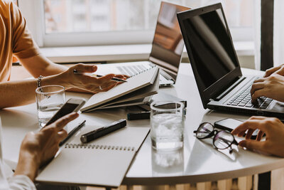 A desk from a team doing SEO. Contains laptop, water, and team members consulting