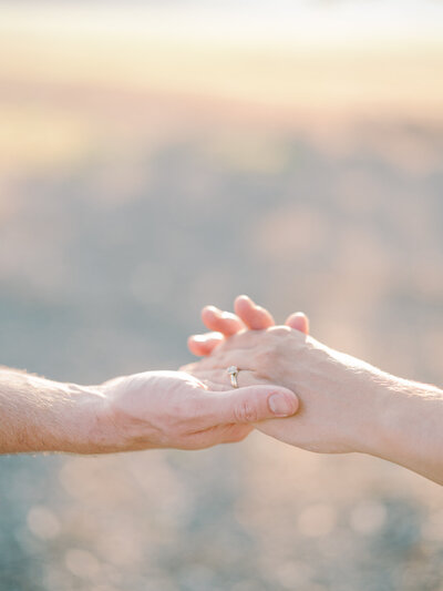 A mother's hand with wedding ring reaches and hold husband's hands in the evening sunlight taken by photographer Little Rock Bailey Feeler Photography