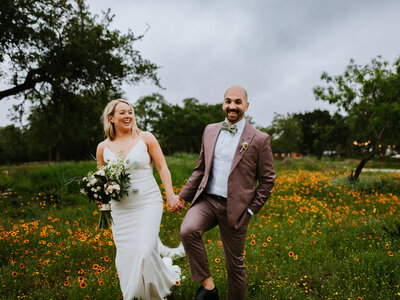 bride and groom walking through wildflowers