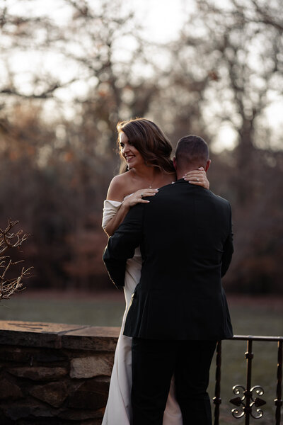 Groom picking up his bride to set her on a stone ledge outside in winter.