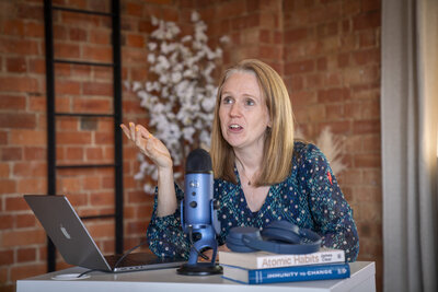 a lady hosting a podcast into a microphone