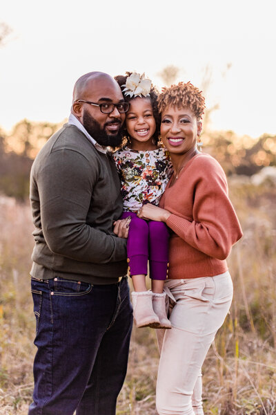 Beautiful African American Family pose in tall field for fall family photos at The Chapel at Livingston in Flora, Mississippi.