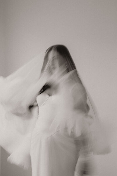 Black and white photo of a bride hidden beneath her veil.