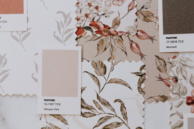 Close-up of floral pattern swatches and Pantone colour chips on a mood board.