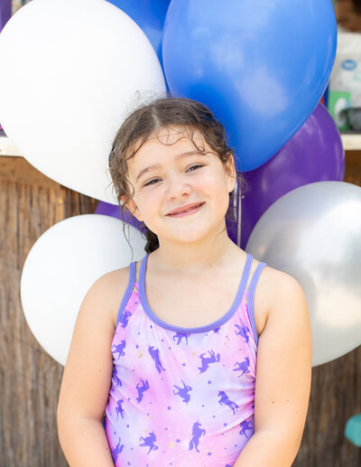 Birthday girl smiles for photo with balloons