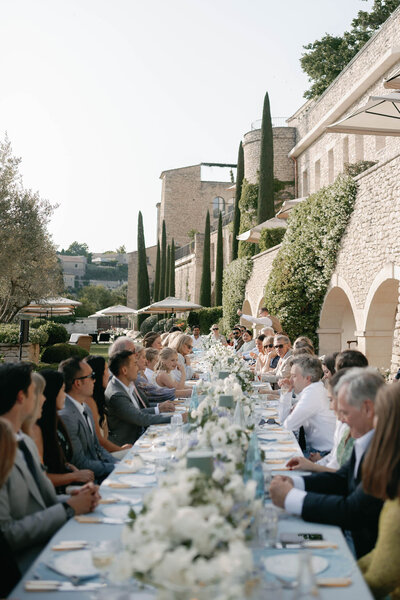 Black and white photo of a Bastide de Gordes wedding dinner featuring a long, rectangular table, soft candlelight and medieval architecture