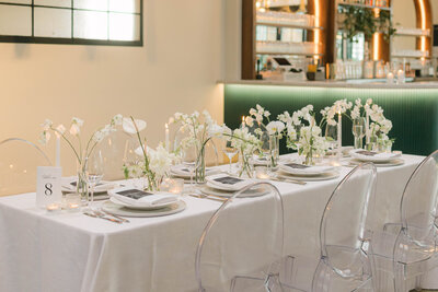 A refined, all-white wedding tablescape with floral arrangements and minimalist place settings, photographed in Milwaukee by Alexia Rodriquez, a luxury wedding photographer capturing timeless and intentional details.