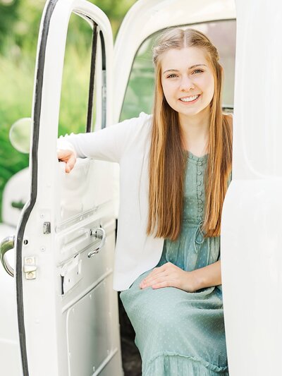 Daughter sitting in a truck by ornamental grasses outdoors.