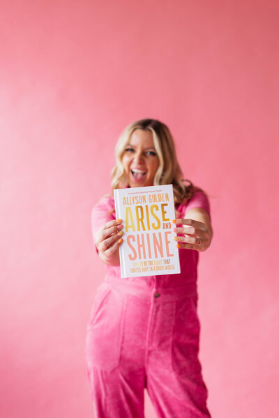 Allyson Golden holding inspiring Christian book "Arise and Shine" this book will help you in times where life feels dark. 
