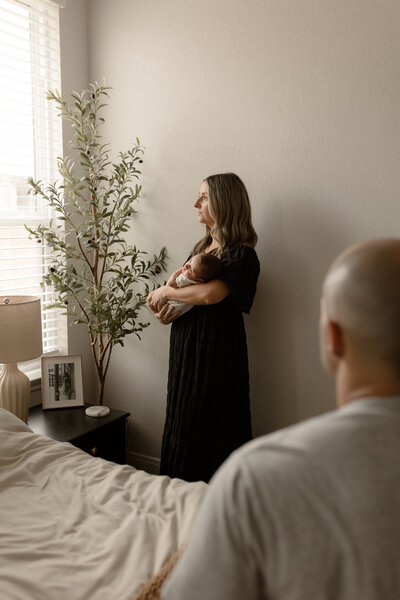 Mom holding newborn while dad looks at them