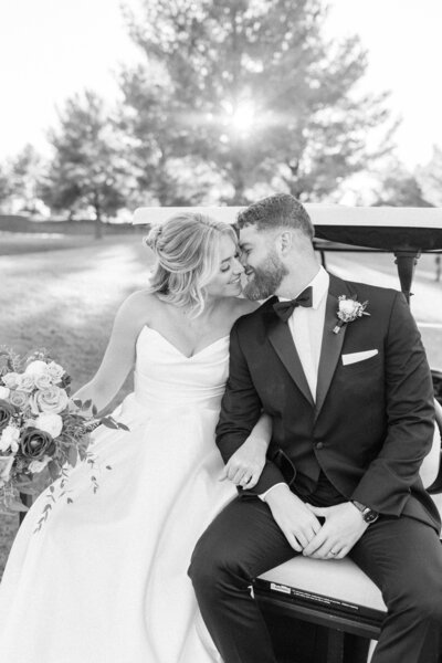 Bride and groom pose in front of pond with autumn colors