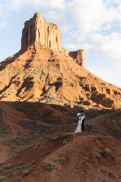 Couple in front of a large mountain at their Moab elopement, by photographer at Forever Framed by Rachel