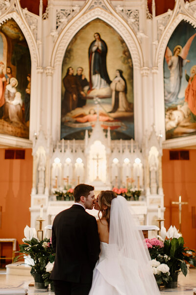 a bride and groom kissing at the altar