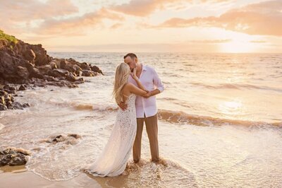 Pregnant couple holding hands in the ocean on Maui photographed by Love + Water