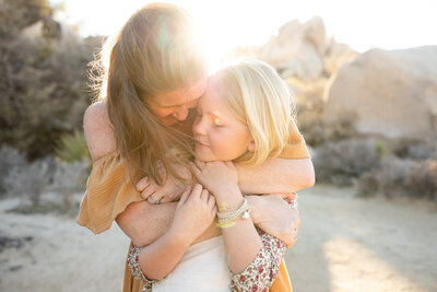 Mom and daughter hugging at sunset at Joshua Tree National Park.