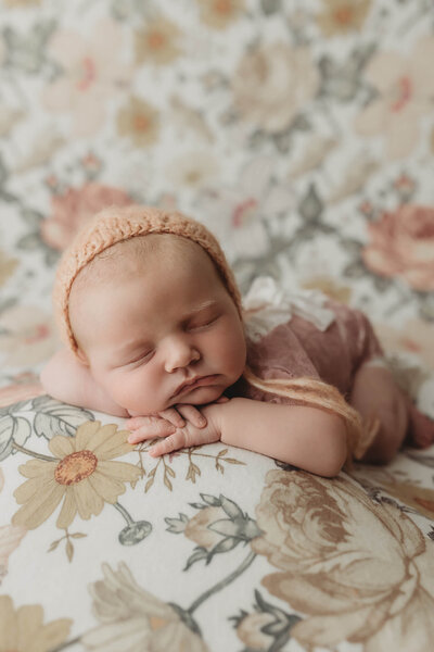 A curious toddler and a relaxed dog peek over the edge of a sofa, watching over a newborn baby, masterfully captured by a Harrisburg newborn photographer, swaddled in a red blanket resting on