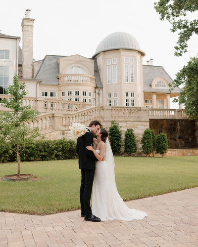 bride and groom kiss by French chateau