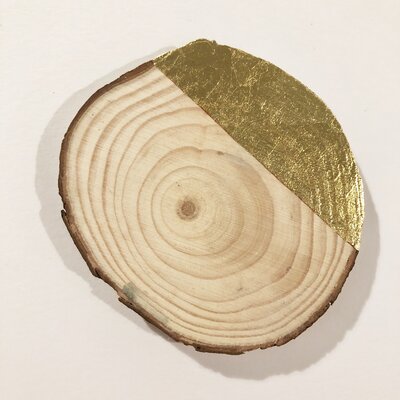 An piece of gilded art, showcasing a shimmering gold leaf applied to a cross-section of a wooden log, highlighting the natural growth rings with a touch of luxury.