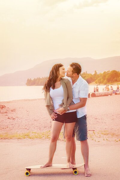 Couple on a long board at a Vancouver beach just about to kiss at sunset.