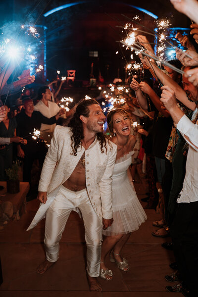Bride and groom laughing under a sparkler tunnel at their wedding exit in Breckenridge, Colorado.