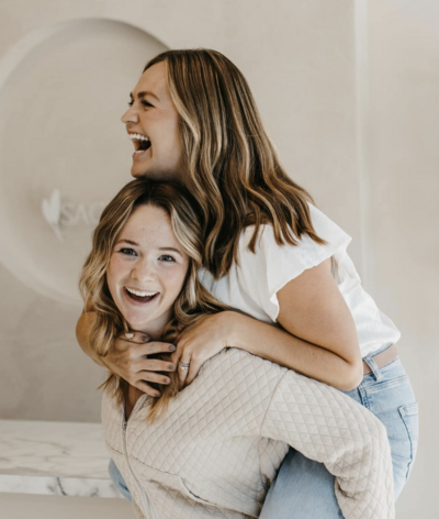 2 blonde woman in white giving a piggyback