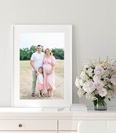 mockup photo of a white wall portrait showing a family of three posing for a maternity session in Austin, TX. 