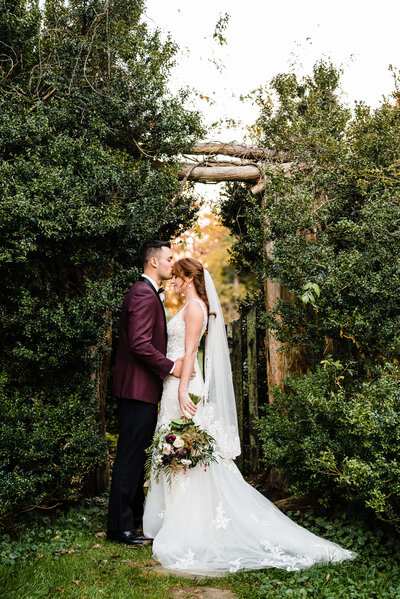 virginia wedding photographer captures garden wedding romantic photos with bride and groom embracing in a lush garden alcove