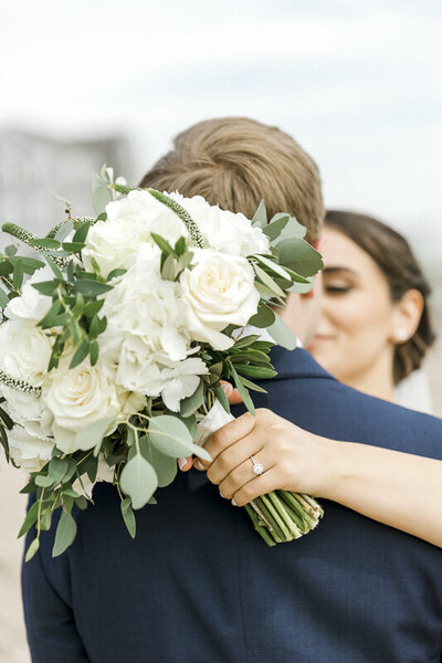 bride hugging groom with florals