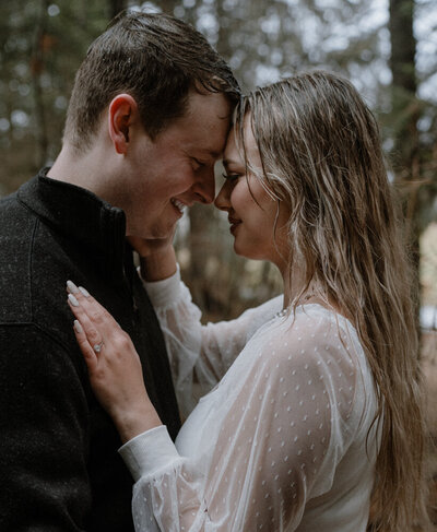 A couple embraces during a romantic winter engagement session in the rain, capturing the moody and intimate atmosphere of Spokane, Washington.