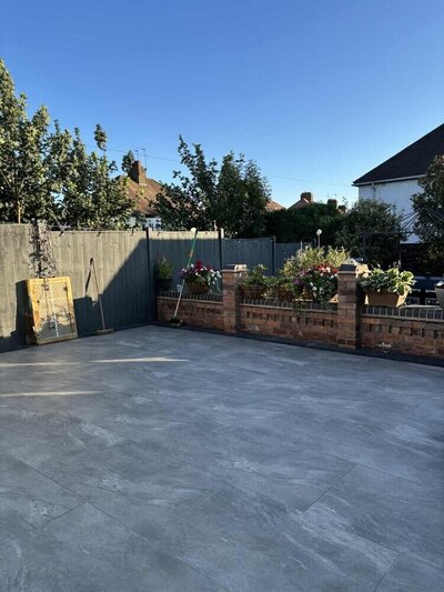 Outdoor patio with large grey tiles and flower-filled planters.