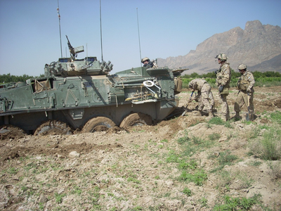 Military team performing fieldwork beside an armored tank, demonstrating operational readiness