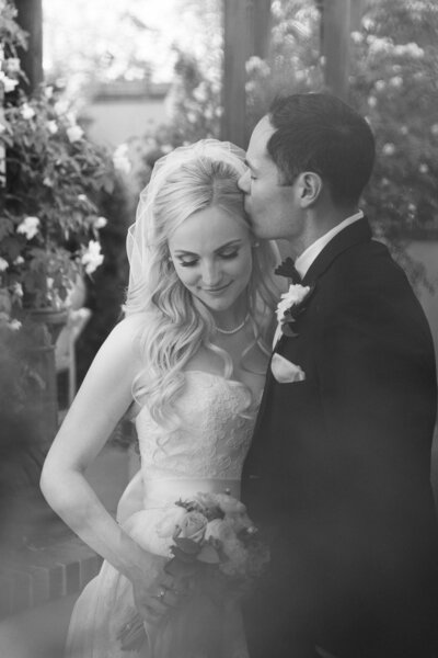 black and white photo of the bride and groom kissing