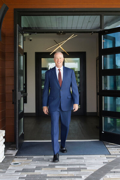 Mark Sullivan in a navy suit and red tie walking out of a building confidently – Life and Health Coach at LifeNBalance Coaching11