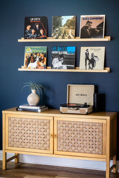 There is a navy blue wall with records displayed above a record player.