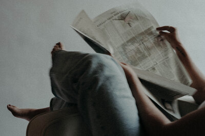person wearing blue jeans opening newspaper
