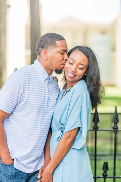 groom kissing bride while she smiles during their dallas texas engagement session
