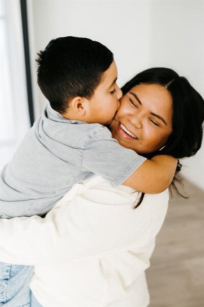 Virginia wedding photographer poses with her son as he sits on a table and she wraps her arms around him