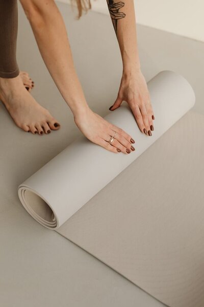 Hands rolling off white pilates mat