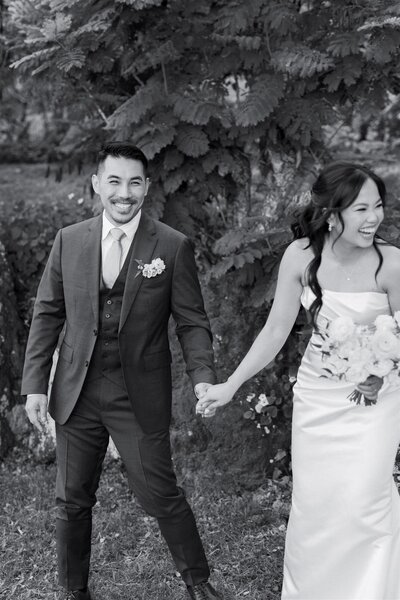 A newlywed couple laughing together and holding hands 