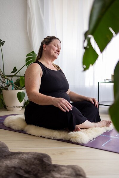 Katie stretches her neck doing yoga for an online private session.