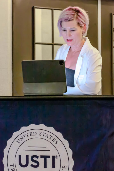 Brieanna Lebo presenting at a conference with a tablet at the United States Trichology Institute podium.