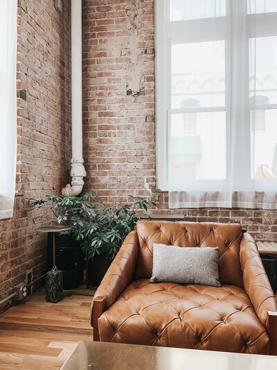 Leather sofa in brick building with plant